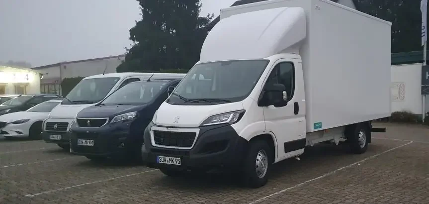 Mehrere Fahrzeuge der Fahrzeugvermietung, darunter Transporter und PKWs, auf einem Parkplatz.